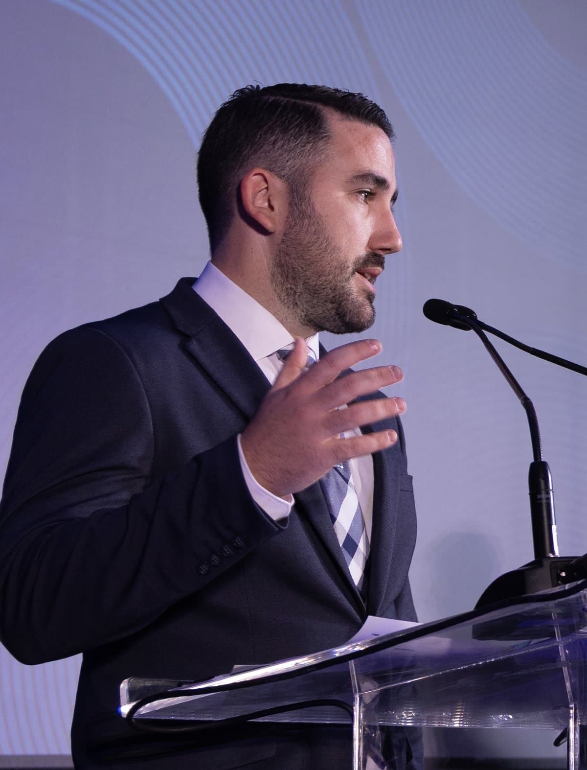 Aldo Ramírez hablando en un podio frente a una pantalla grande en un evento de premiación de la industria.
